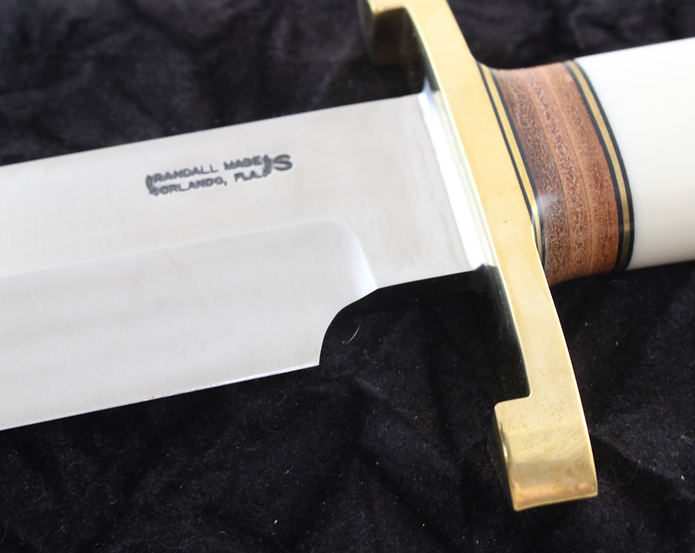 Knife with a wooden handle and brass guard on a black background
