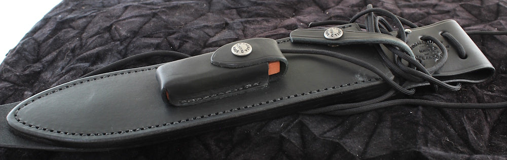 Black leather sheath with a knife on a textured black background