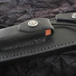 Black leather sheath with a knife on a textured black background