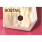 Close-up of a wooden instrument with 'BOBTAIL' branding on a red background